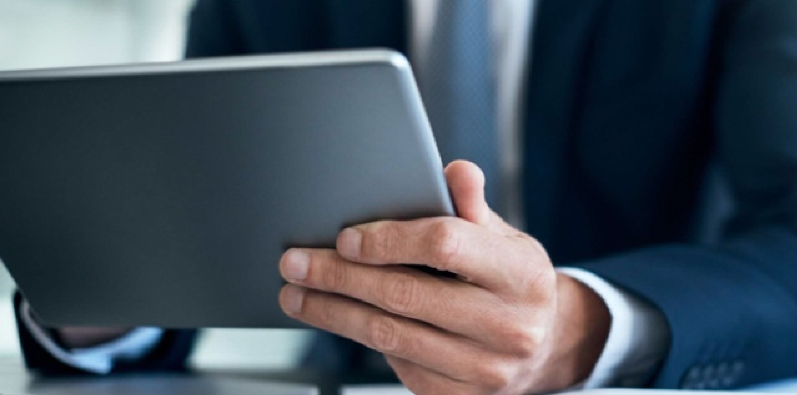 Close-up of a business professional holding a tablet.