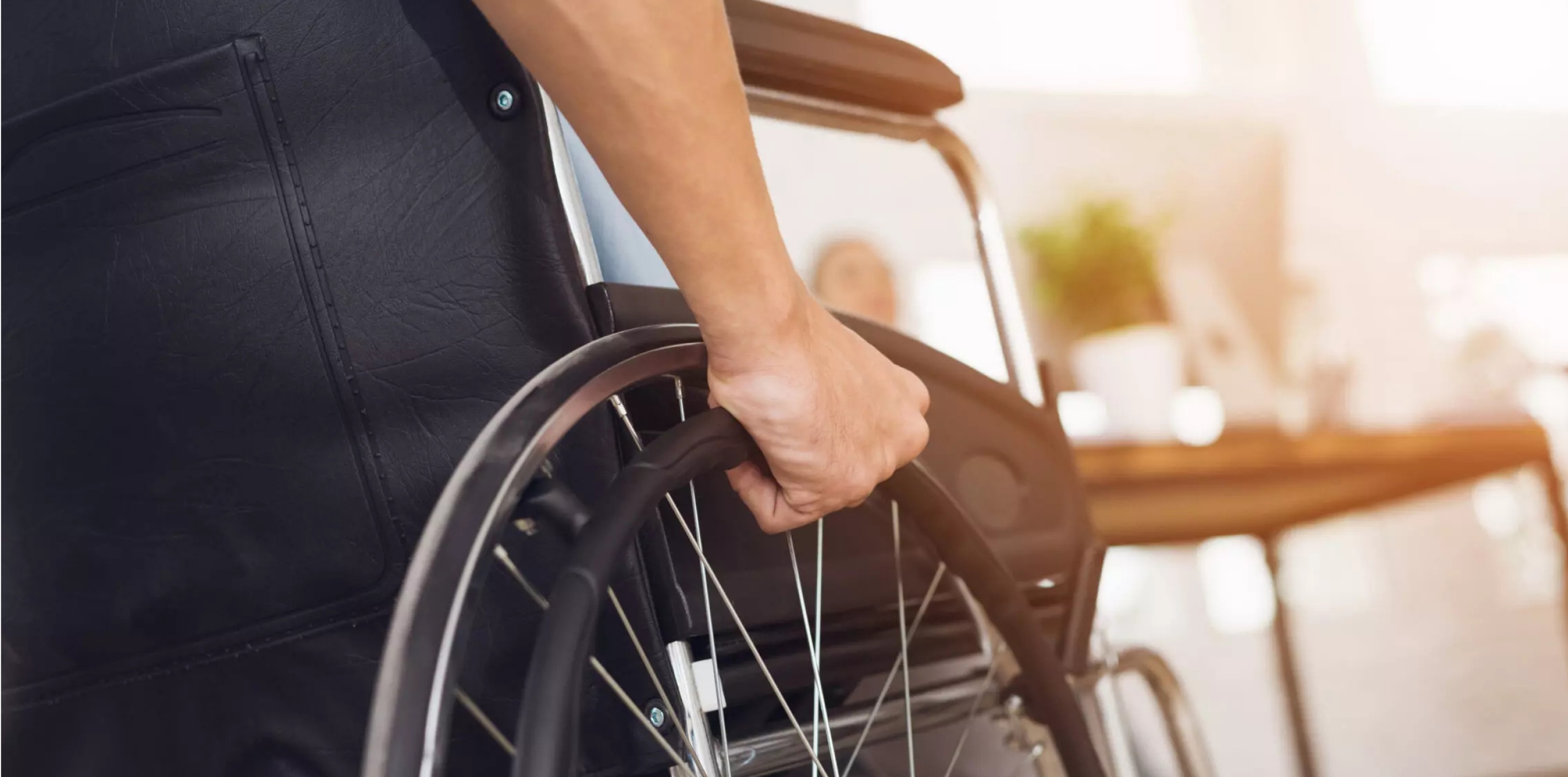 Close-up of a hand gripping the push rim of a wheelchair.