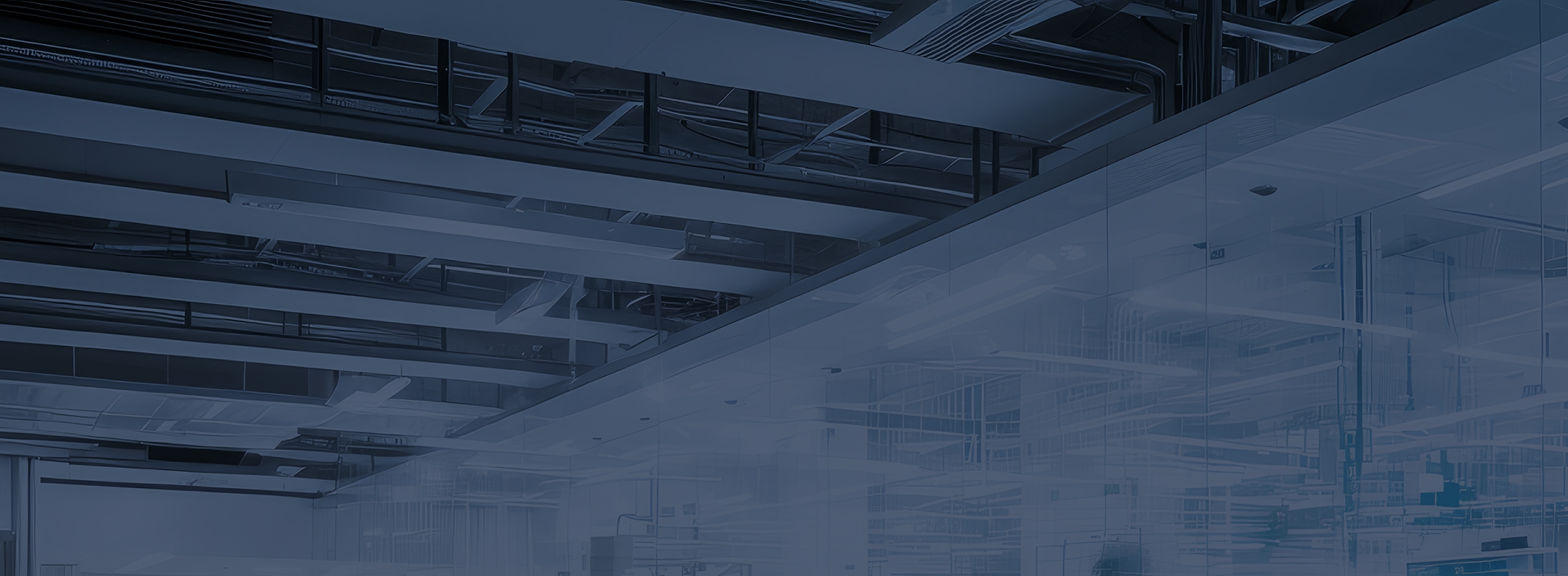 Exposed ceiling beams and ductwork above a glass-walled industrial workspace.