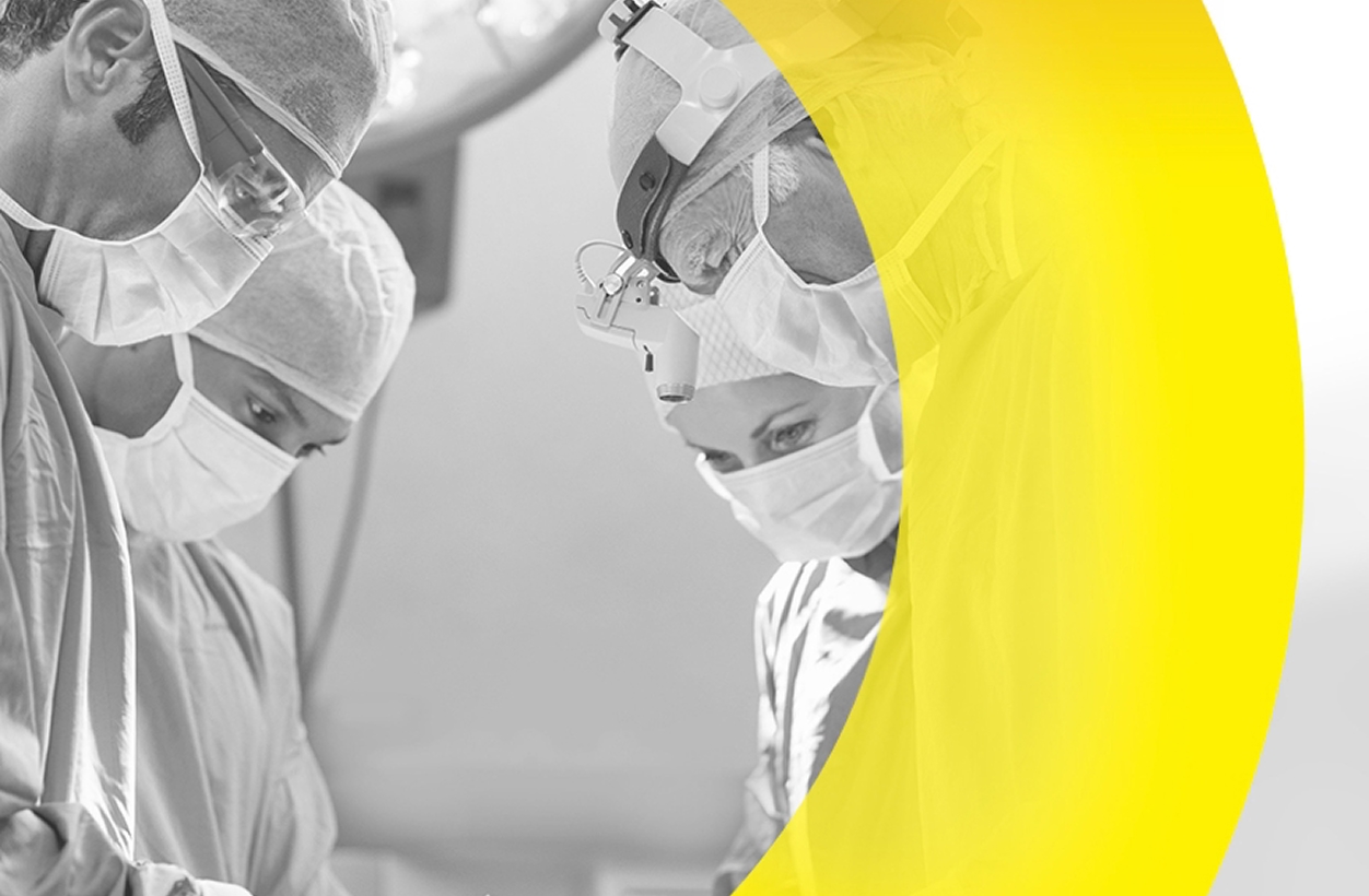 Surgeons focused on a procedure in an operating room, with a yellow graphic overlay.