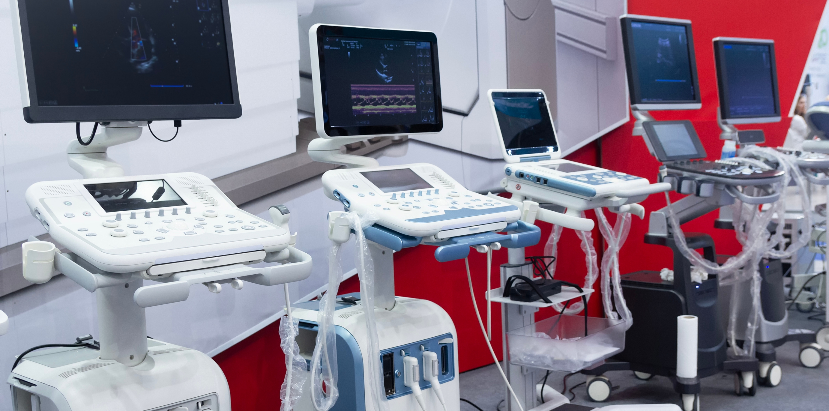 Row of diagnostic ultrasound machines on wheeled carts at a medical equipment expo.
