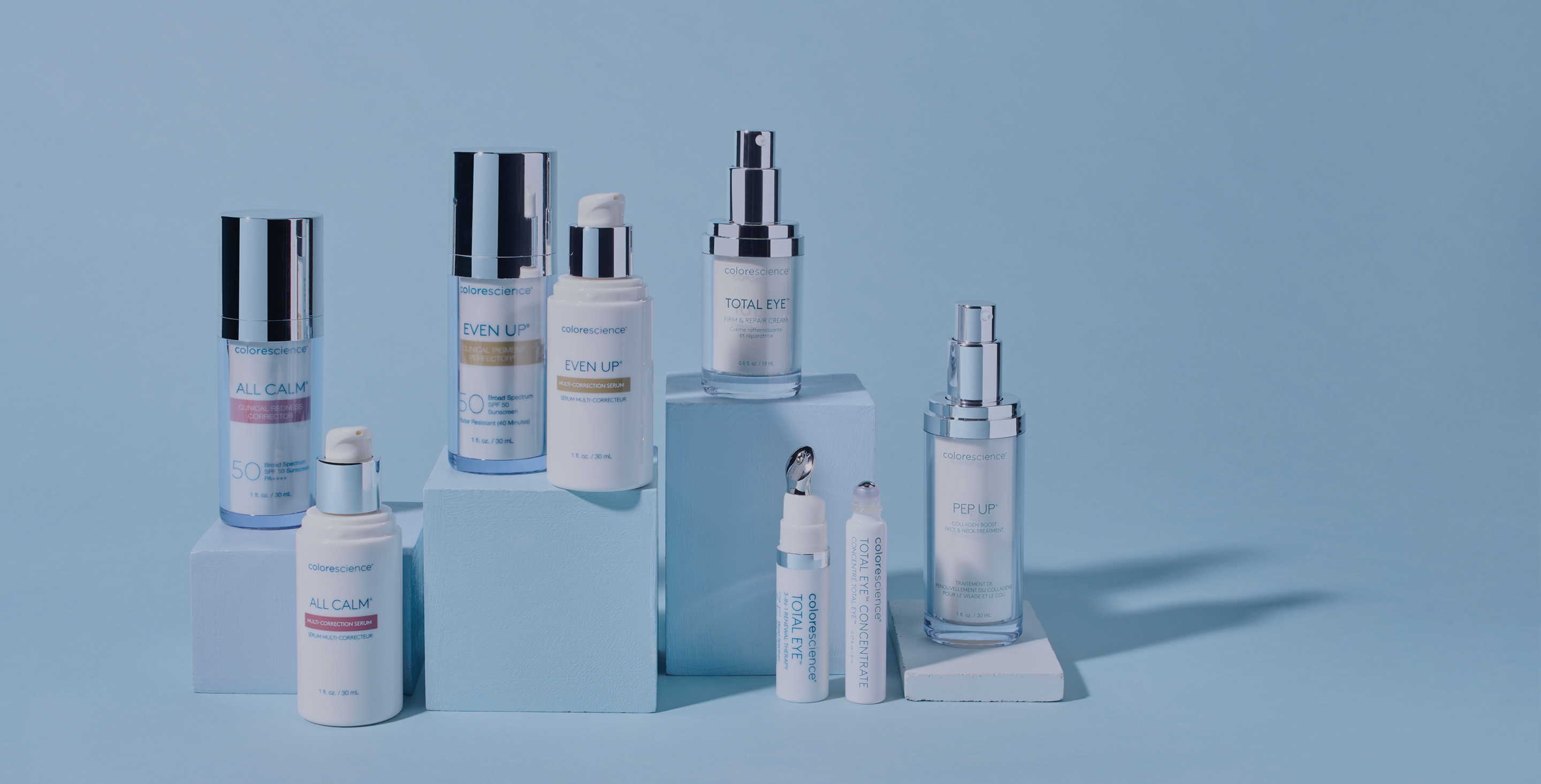 Colorescience skincare product lineup—bottles and tubes displayed on blue blocks against a light blue background.